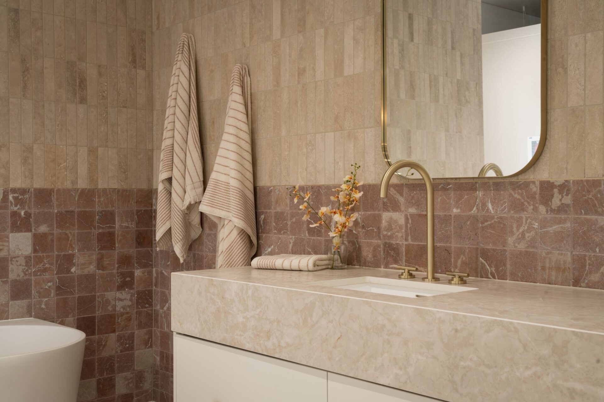 Bathroom display with stone vanity, brass tapware and terracotta tiles