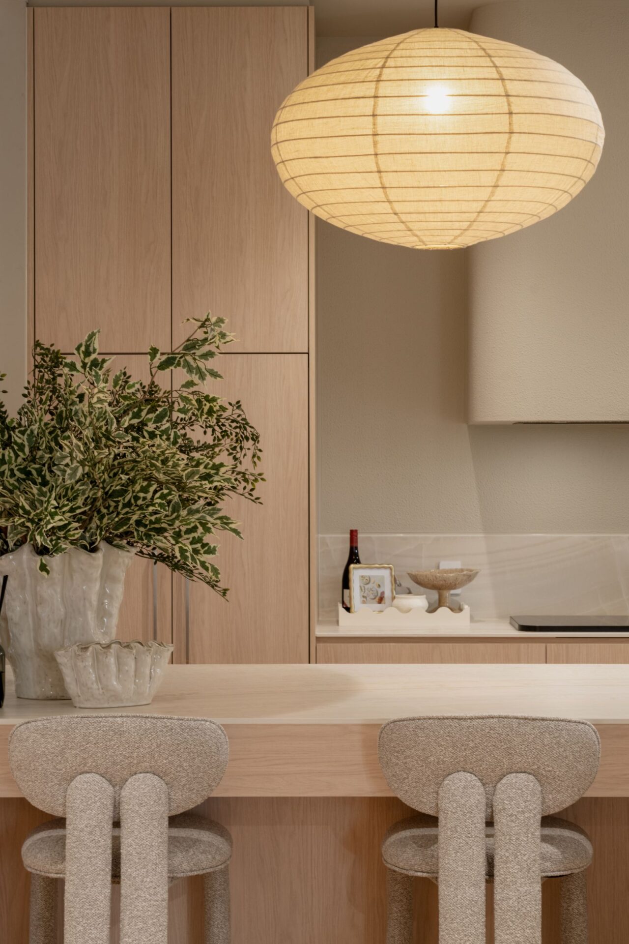 Kitchen detail with paper lantern, oak cabinetry and boucle stools