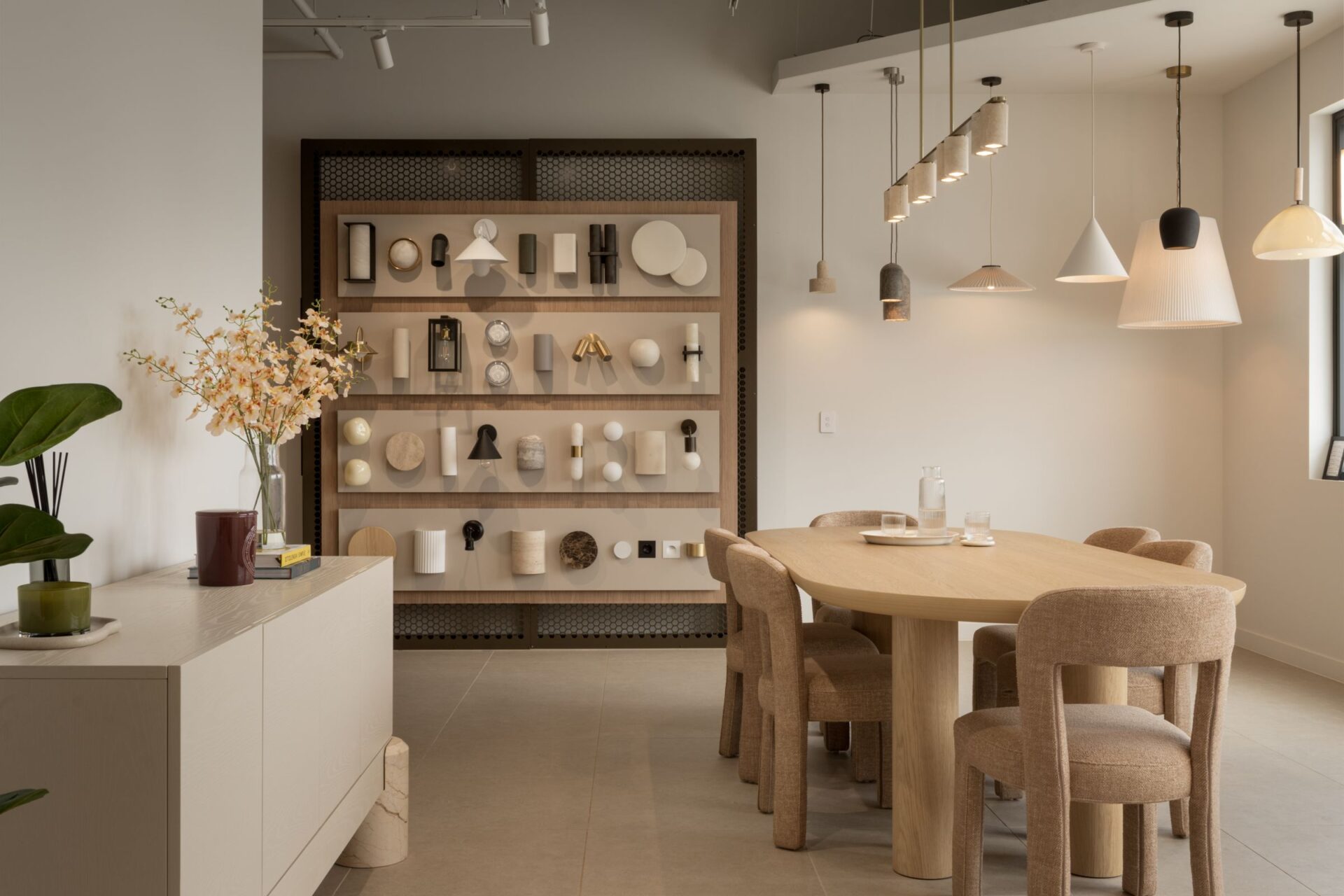 Pendant lights above a timber dining table with a feature shelf behind